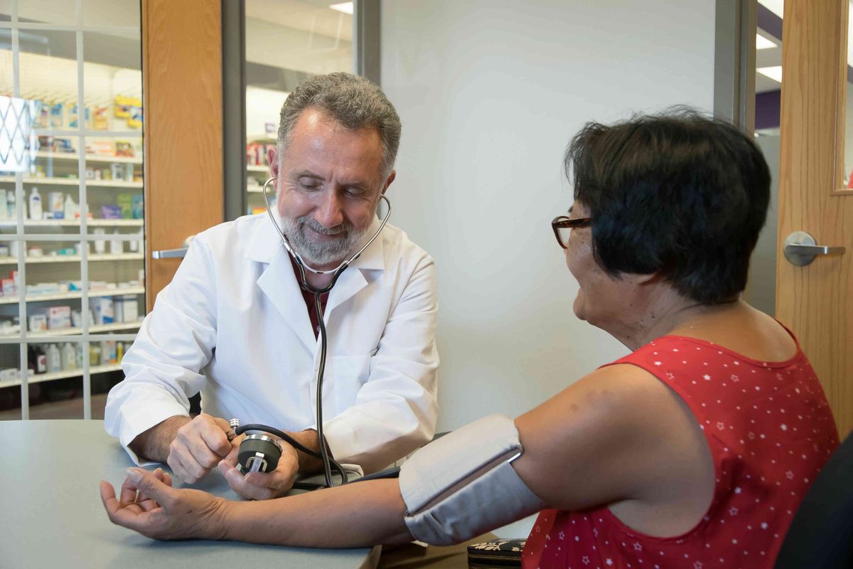 A pharmacist takes a person's blood pressure Health screening